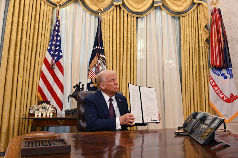Donald Trump displaying an executive order in the Oval Office