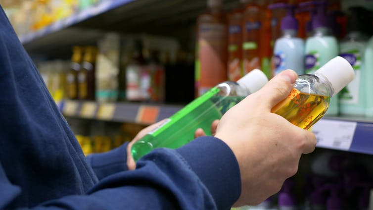 A man in a store chooses a shower gel, carefully reads the bottle