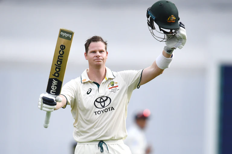 Steve Smith raises his bat to celebrate a century