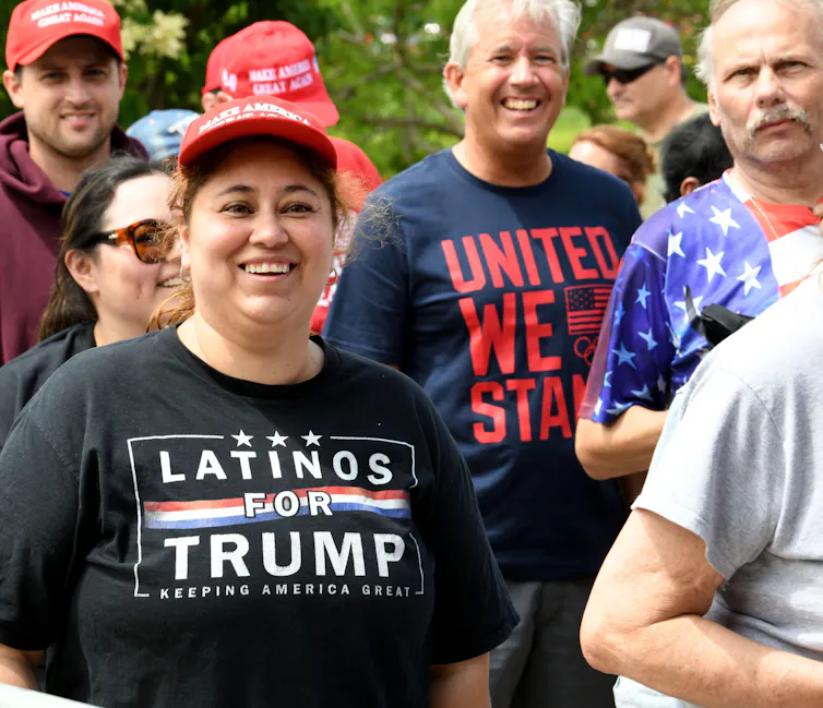 A woman in a Latinos for Trump t-shirt with other supporters of DOnald Trump before the 2024 US election