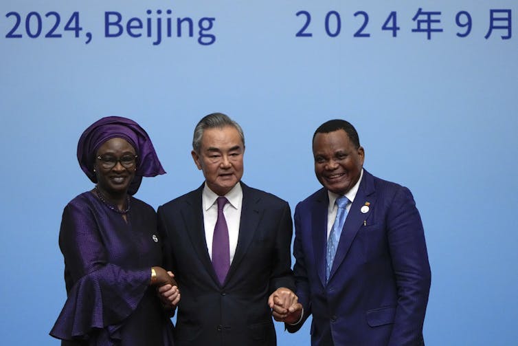 Three people hold hands on stage.