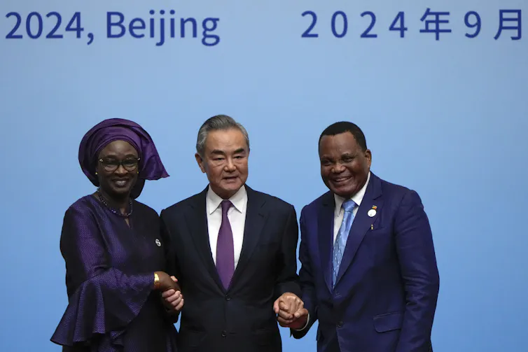 Three people hold hands on stage.