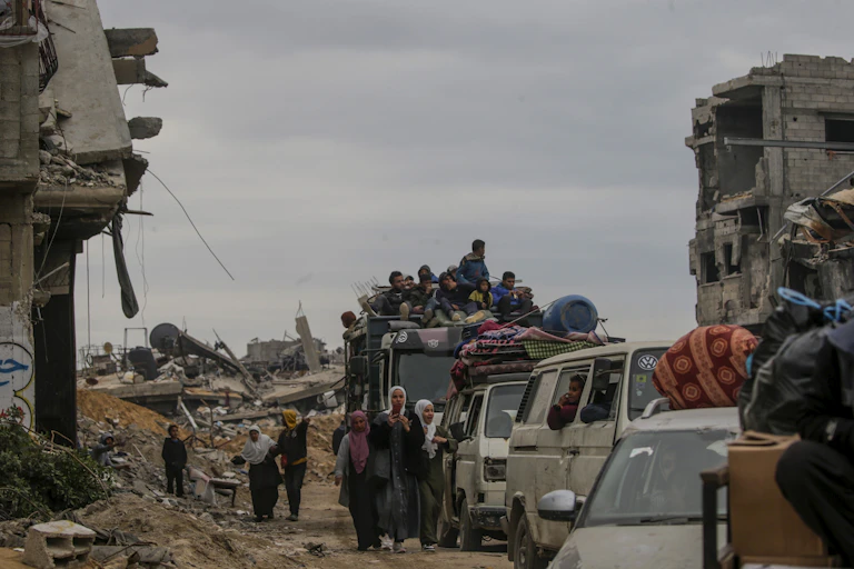 Palestinian civilians make their waqy home through rubble-strewn streets