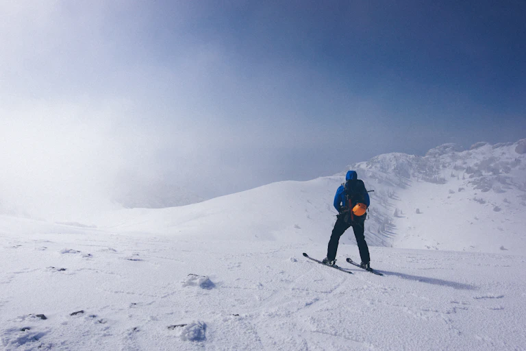 Un skieur en haut d’une piste de ski, par beau temps