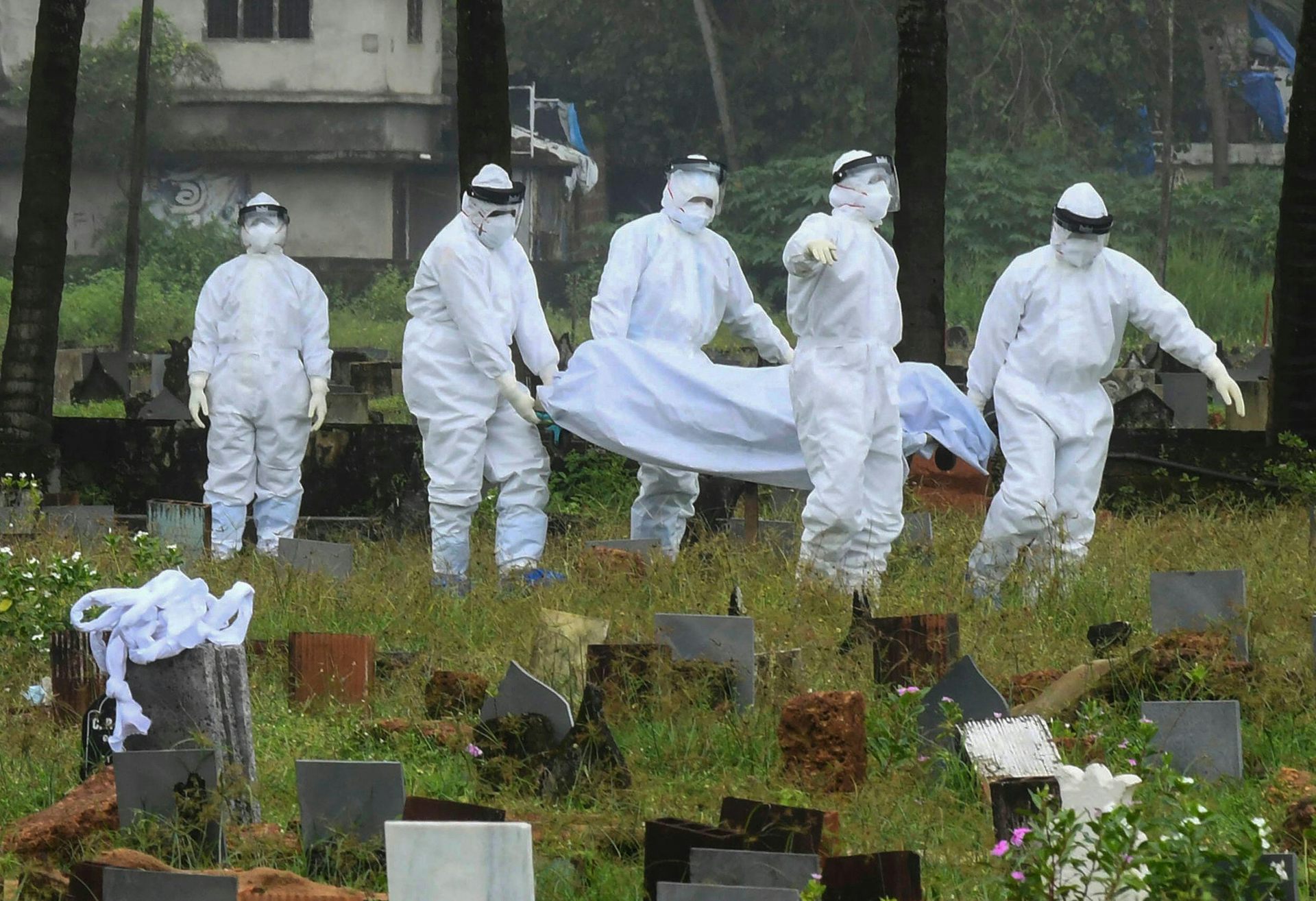 People in protective suits prepare to cremate the body of a boy died of the Nipah virus in Kerala, India in the 2021 outbreak.