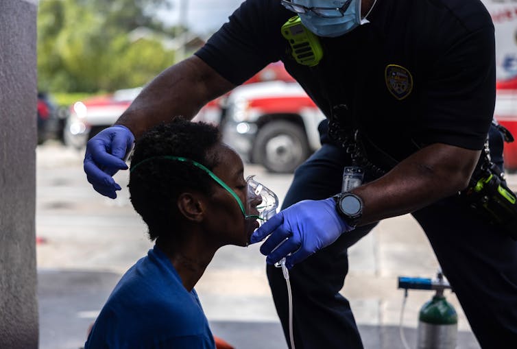 A paramedic places an oxygen mask on the face of a woman.