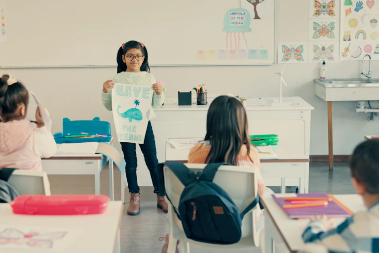 girl holding whale poster at front of class showing schoolchildren