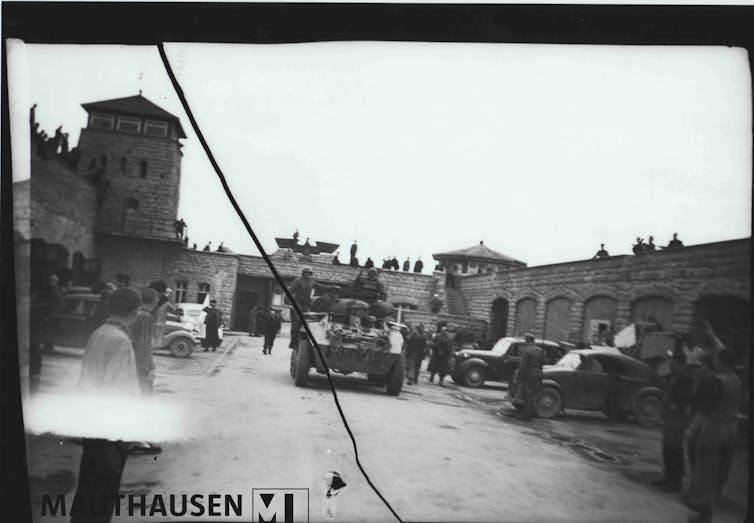 Black-and-white image of tanks roling into a concentration camp
