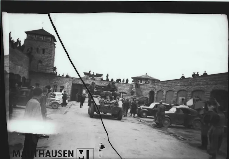 Black-and-white image of tanks roling into a concentration camp