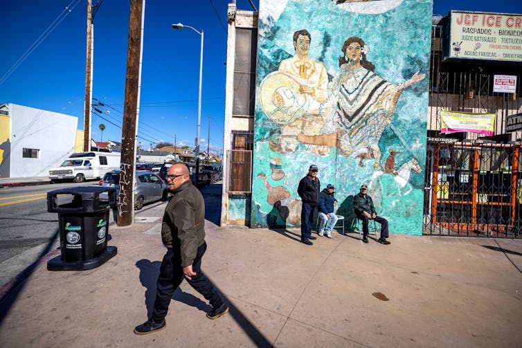 A man walks past a mural of mariachi musicians in Boyle Heights.