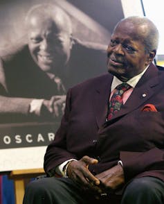 A man smiling with his likeness behind him.