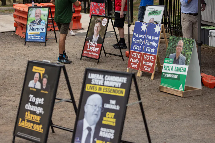 Several small political billboards standing on a footpath