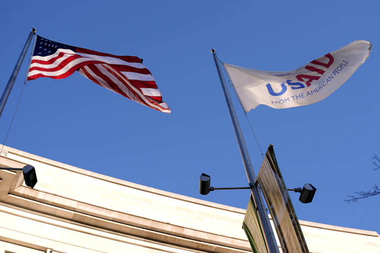 A U.S. flag and a white flag reading 'USAID from the American people'