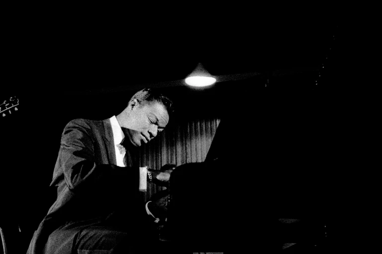 A young Black man, deeply immersed in the music he is playing.