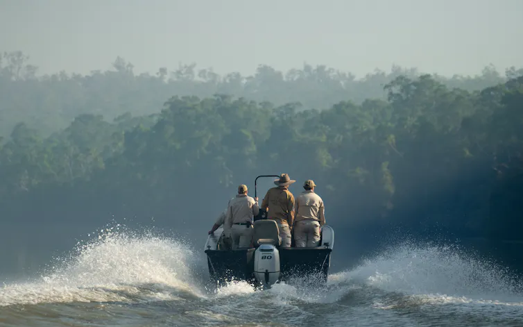 Rear view of a group of researchers on a boat in the Wenlock River, Queensland.