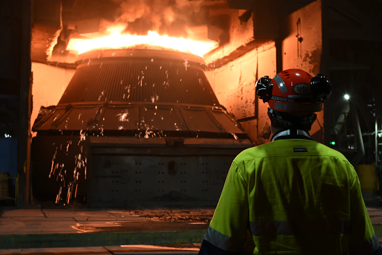Worker standing in front of blast furnace at BlueScope steelworks in Port Kembla