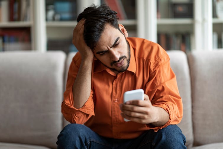 A man who appears stressed looking at his phone.