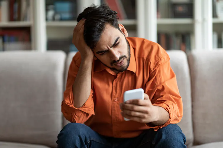 A man who appears stressed looking at his phone.
