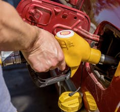 A man hand holding pump filling car with gasoline