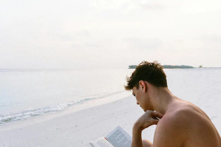 man reading on beach