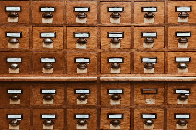 A wall of little brown archival drawers with labels on them.