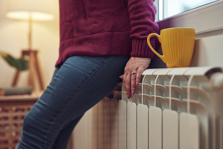 A person leaning on a radiator.