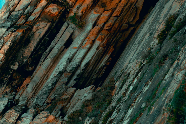a mountain side with a rock face and a blue sky in the background
