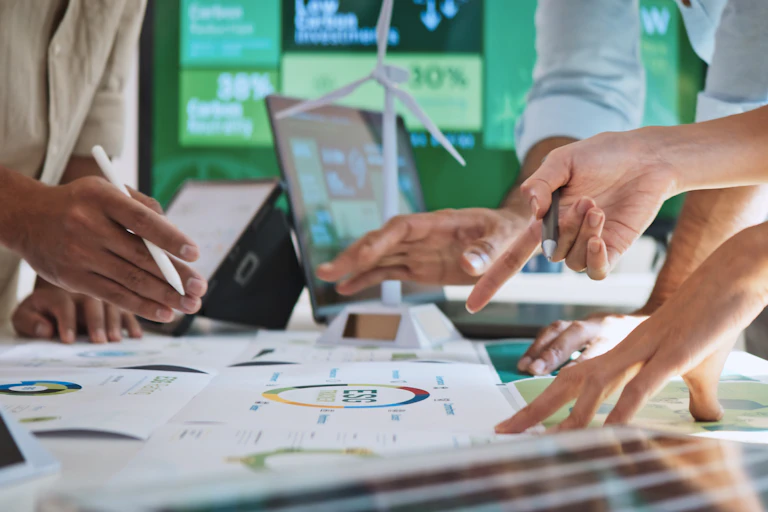 colleagues standing over a desk working on sustainability in the workplace