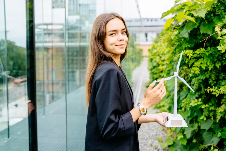 young female professional holding a miniature wind turbine