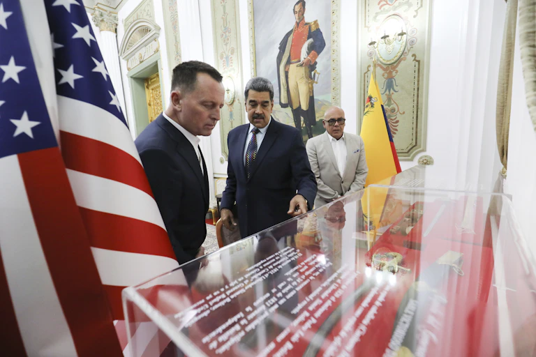 Thre men look into a glass cabinet.