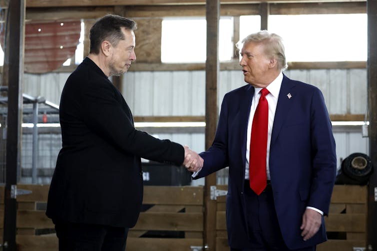 Two men in business suits shake hands.