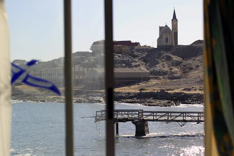 A photo of a hill near a body of water with a church and other buildings at the top.