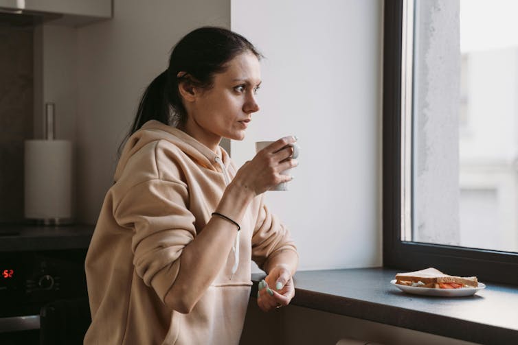 Woman drinks tea, looking out the window