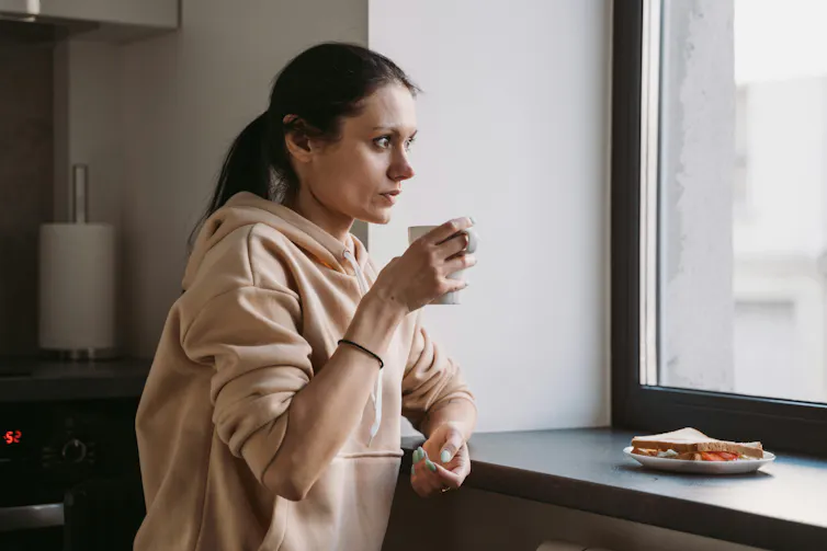 Woman drinks tea, looking out the window
