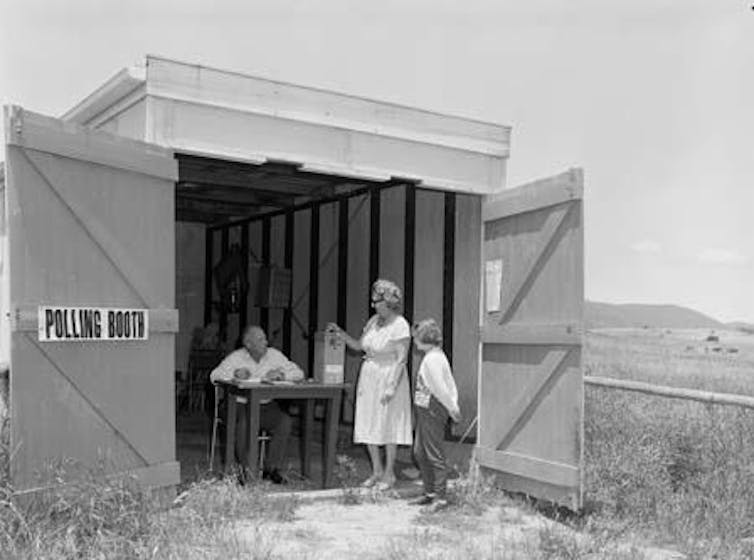 A woman and her son put a vote in a ballot box at a remote polling station in the 1960s.