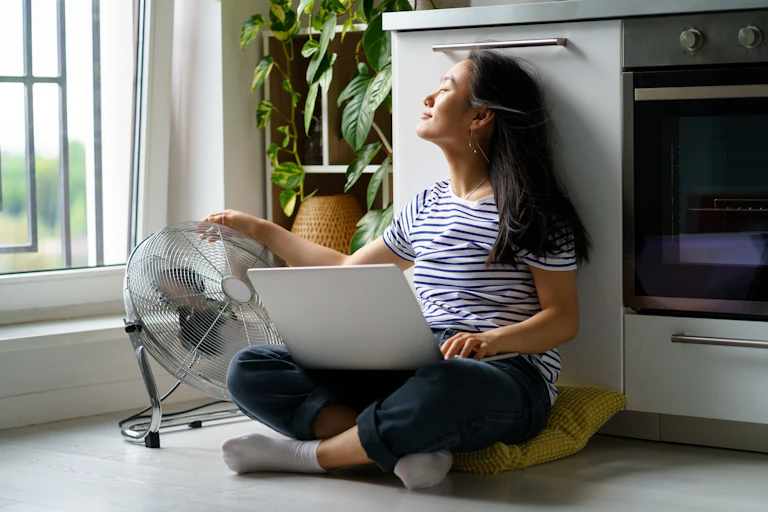 Midlife woman is cooled by a fan