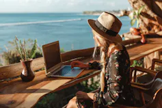 Woman overlooking beach working on a laptop