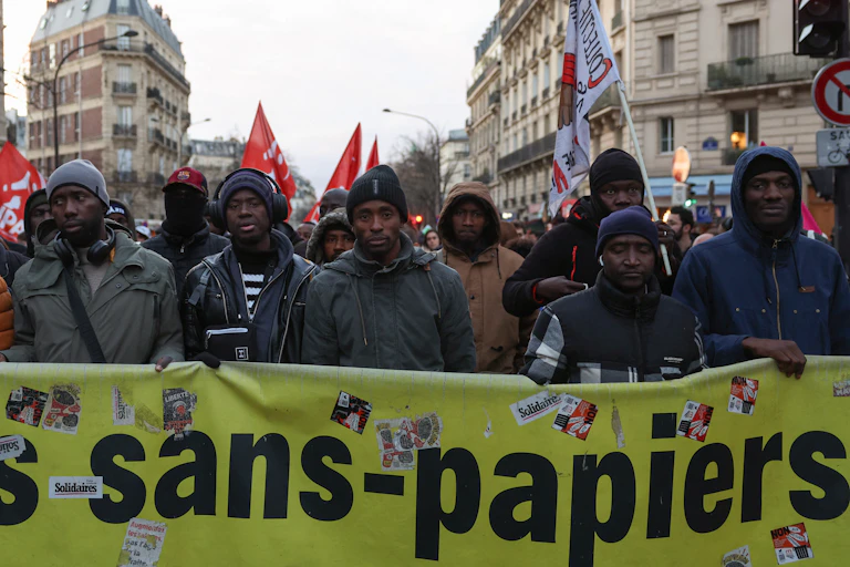 Manifestants derrière une banderole où on lit « les sans-papiers »