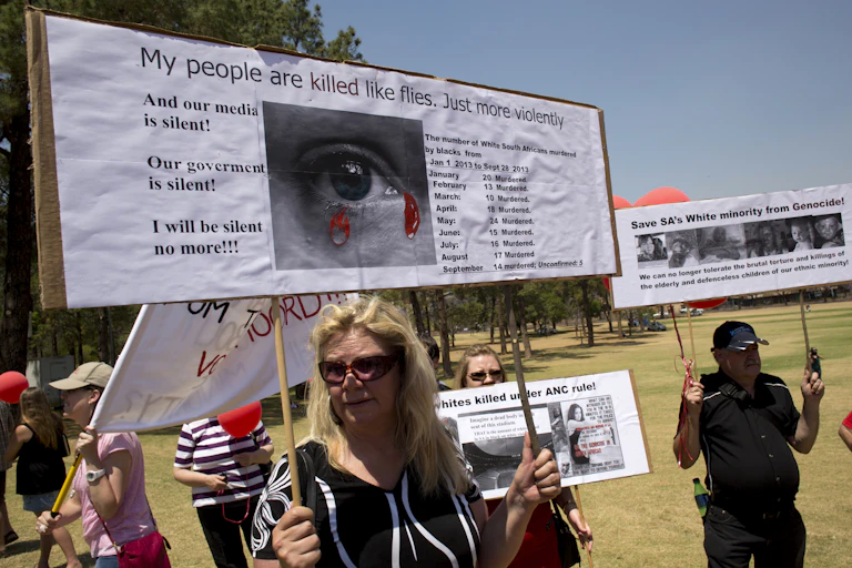 White South Africans hold placards during a protest against the violent murder of farmers which they term "genocide and oppressive state policies in favour of blacks" in Pretoria.