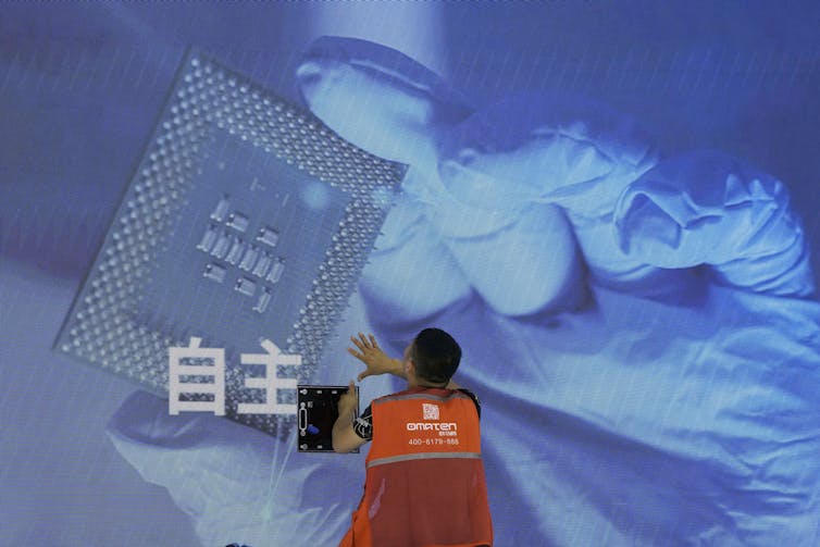 A worker checks a Chinese-language display panel at an AI conference.