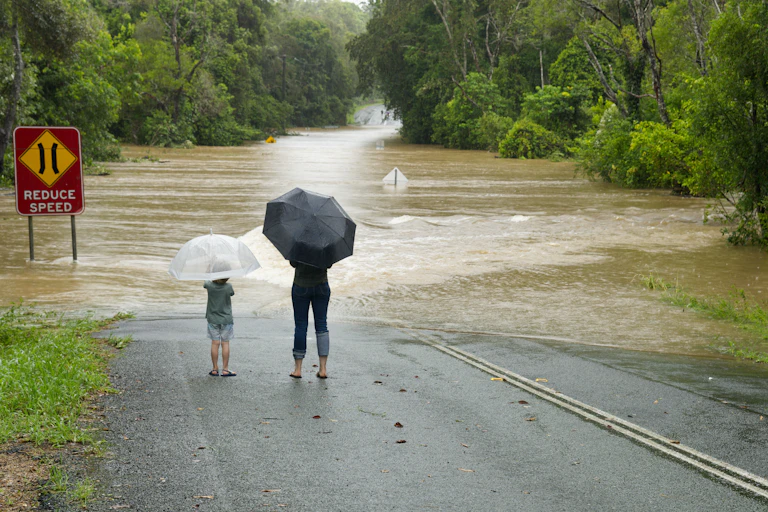 Deux personnes devant une route inondée dans l'état de Queensland, Australie.