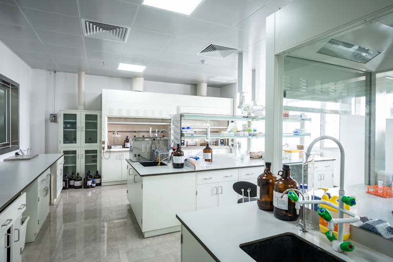 A science lab, with lab benches, containers of liquid, a fume hood and sinks.