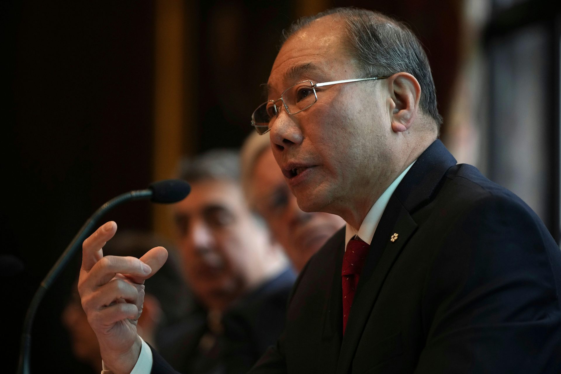 Shoo Lee gestures while speaking into a microphone at a press conference