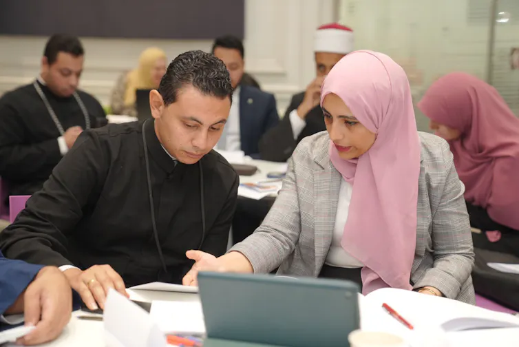 people sat at laptop at table at a climate and religion workshop