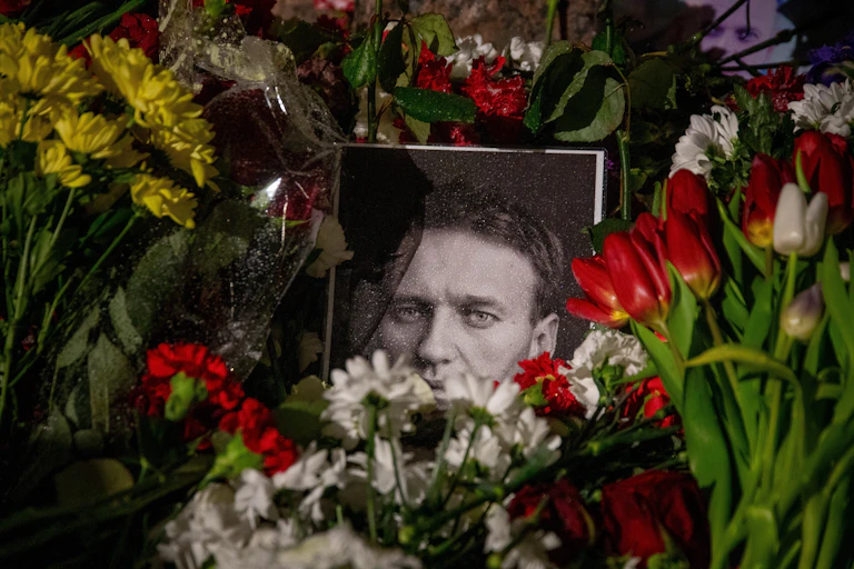 Black-and-white photo of Alexei Navalny surrounded by flowers.
