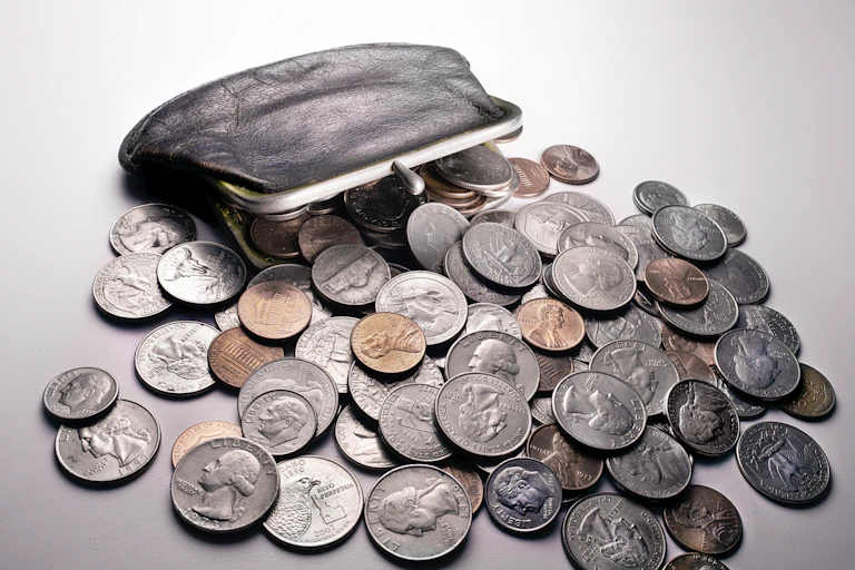 A dark brown change purse from which coins are spilling.