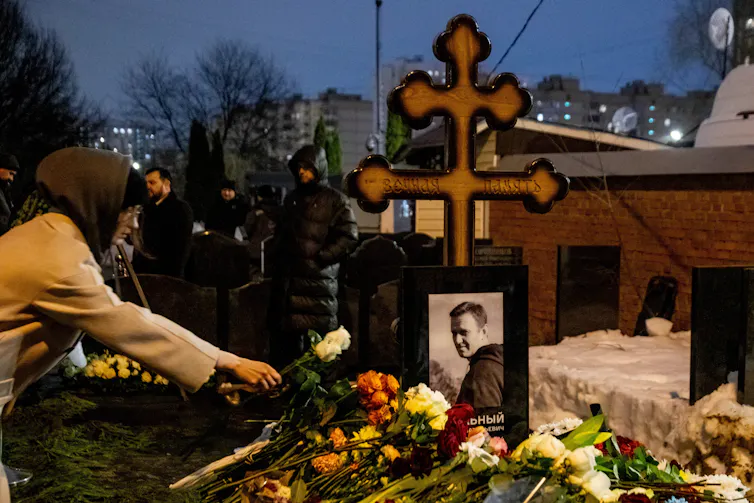 A mourner adds a flower to the grave Alexei Navalny