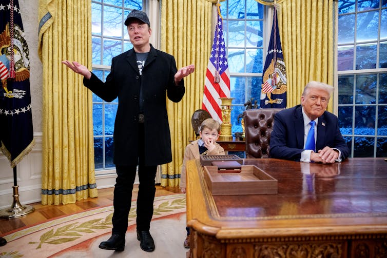 Two men and a small child in an elegant room with yellow curtains.