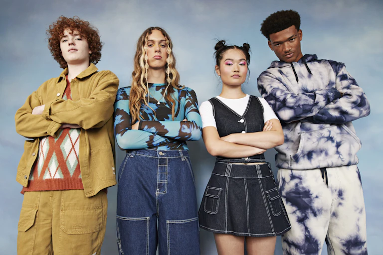 Portrait of serious teenage female and male friends with arms crossed standing against colored background.