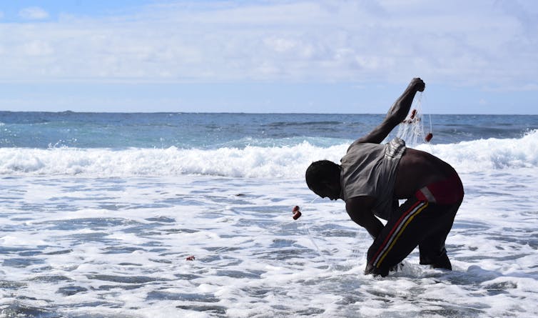 A person gathering up a fishing net in Vanuatu